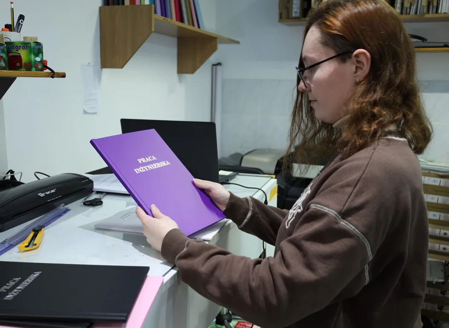 Pracowniczka Drukorz sprawdza twardą oprawę pracy inżynierskiej