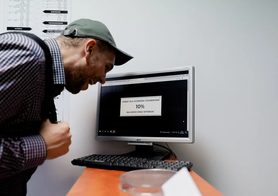 Klient przy ekranie z informacją o rabacie 10% dla uczniów i studentów na ksero i wydruki