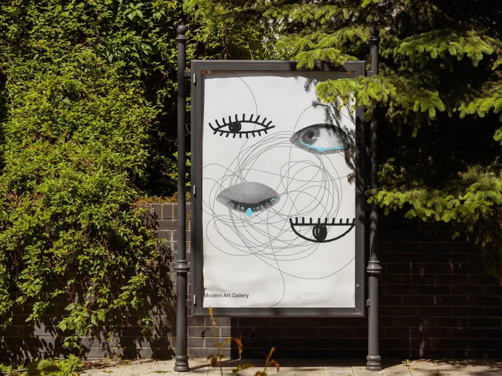 Plakat z grafiką oczu w gablocie reklamowej przy ulicy, wśród zieleni
